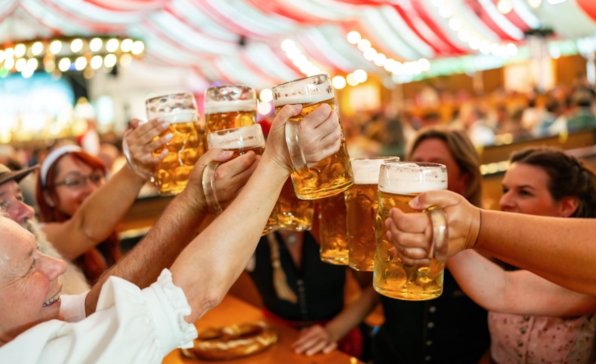 People toasting with large mugs of beer at a festival.