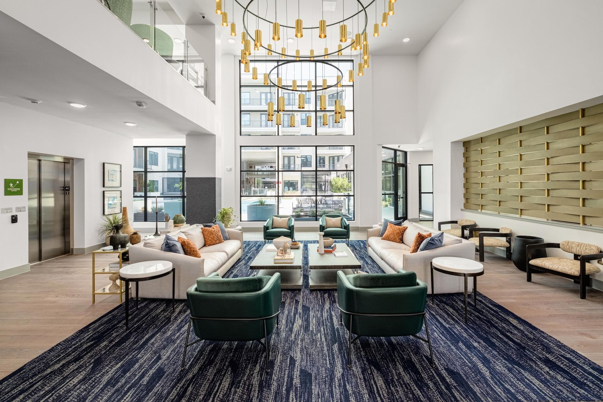 Lobby with sofas, armchairs, and a large chandelier, hardwood floors, and large windows.