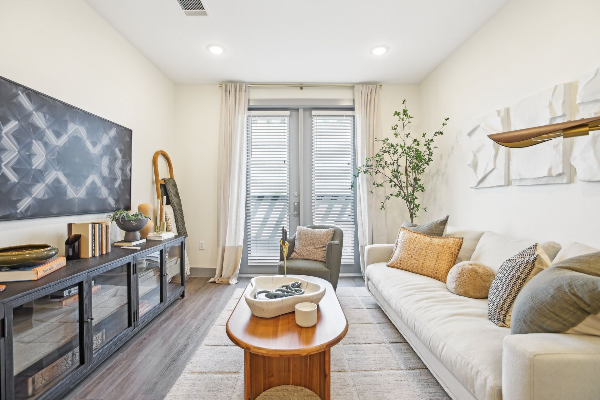 Living room with a sofa, coffee table, and large window. Neutral tones and modern decor.