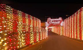 Tunnel entrance illuminated with red, white, and gold Christmas lights, leading to a sign that reads 