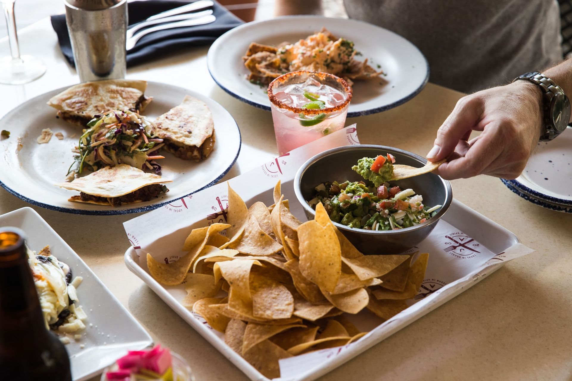 A person is dipping a tortilla chip into a bowl of guacamole.