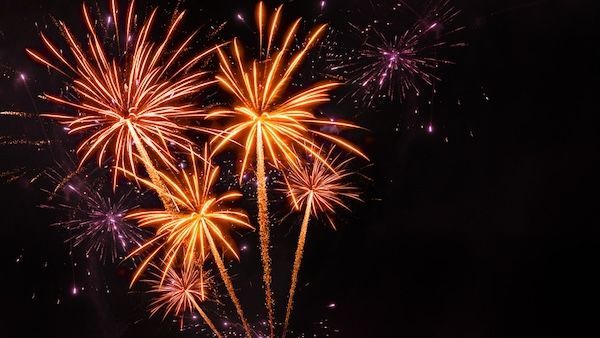 A bunch of fireworks are exploding in the night sky.
