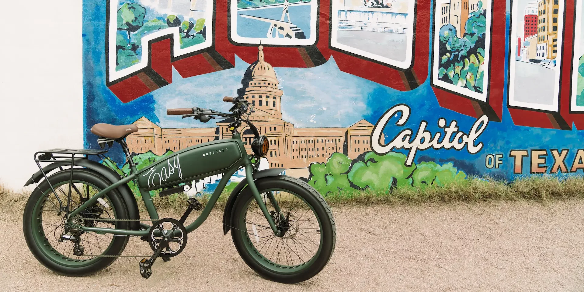 A bicycle is parked in front of a mural that says capitol of texas
