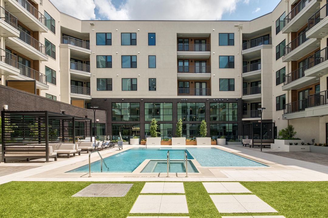 Courtyard of modern apartment complex with pool and lounging area.