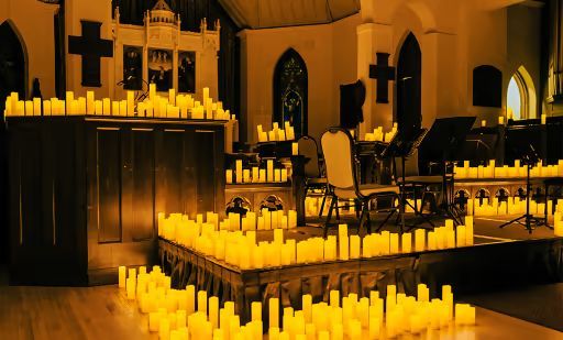 A church interior lit by many candles. Wooden altar, crosses, and a few musicians.