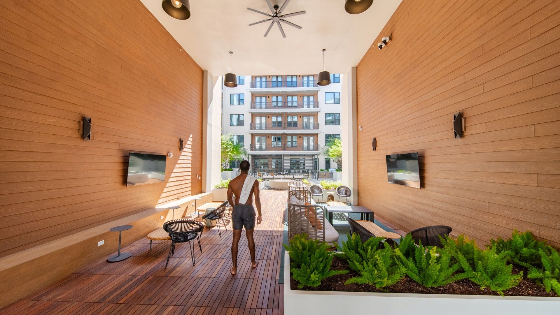 a person walking outside with wooden walls and outdoor tvs
