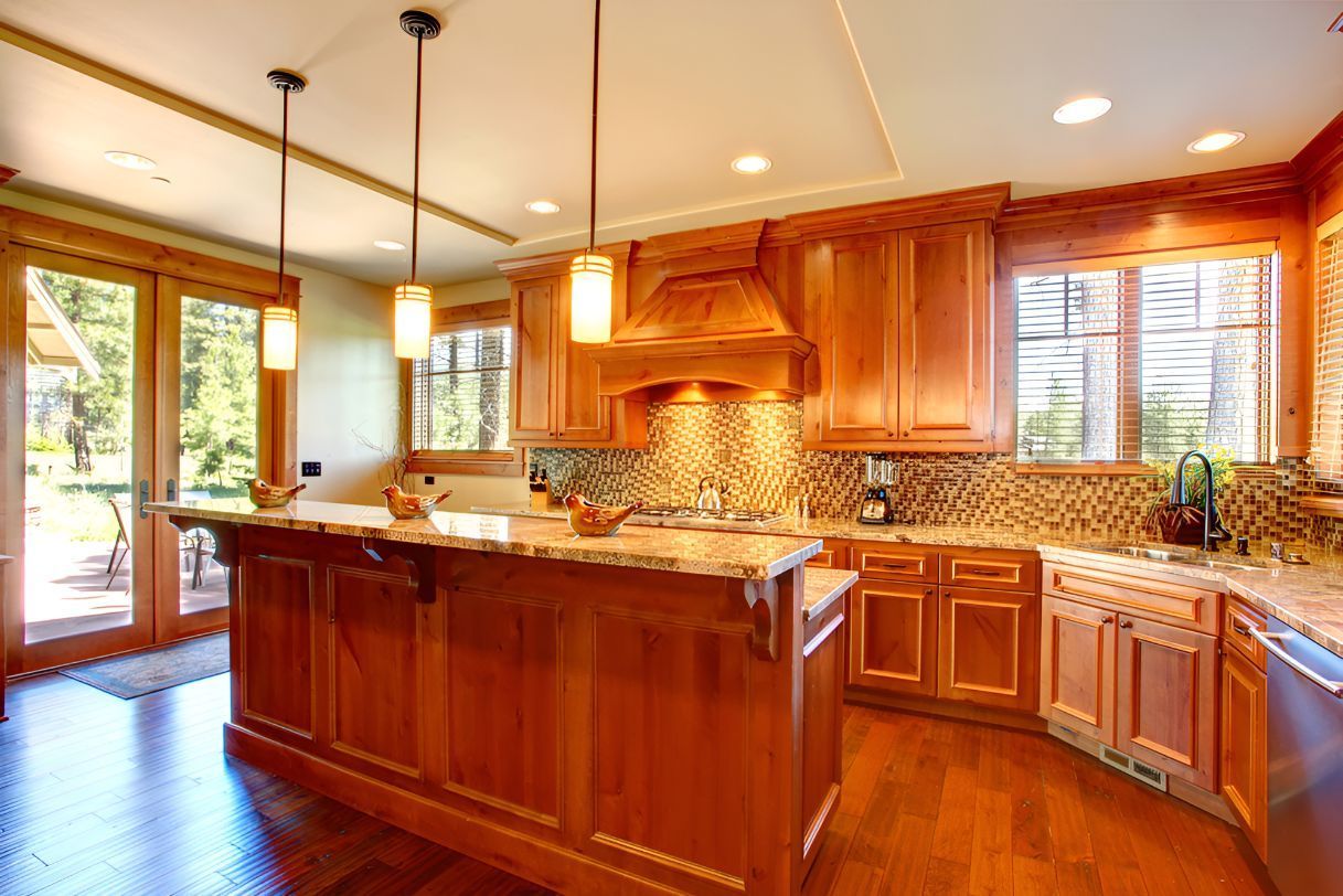 A Kitchen With Wooden Cabinets, Granite Counter Tops, and Sliding Glass Doors — Foreshore Kitchens In Yandina, QLD