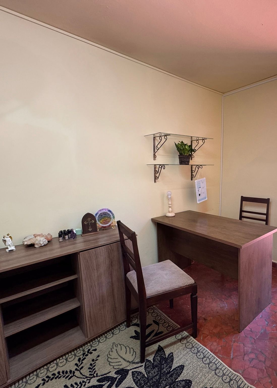 Uma sala com uma escrivaninha, cadeira, prateleiras e um tapete.