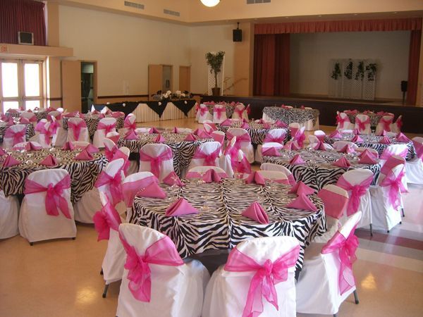 Banquet hall set with round tables and chairs covered in white and pink zebra-print sashes