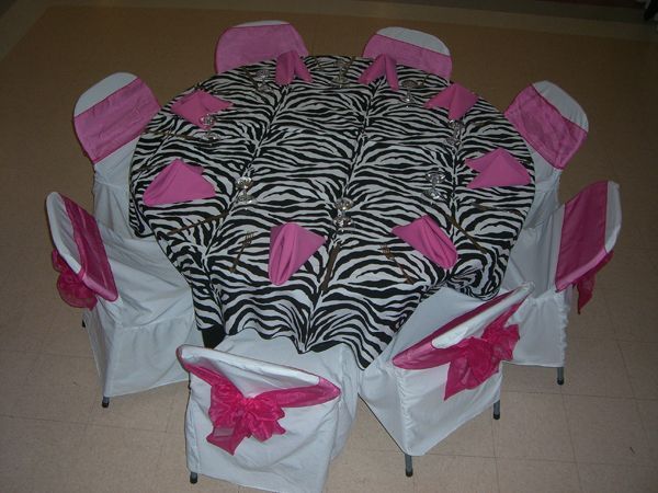 Round table with zebra-print cloth and white chair covers with pink bows around it