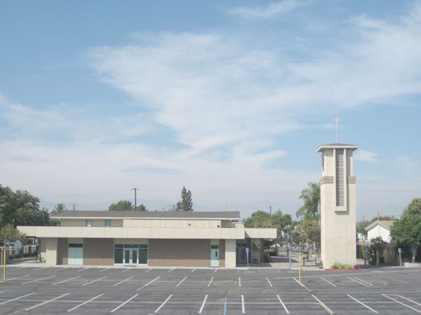 Empty parking lot beside a low building and tall white tower under a blue sky