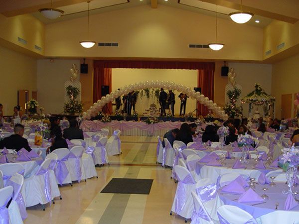 Banquet hall decorated with white tables, purple accents, and a stage at the front