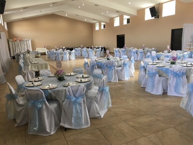 Banquet hall with round tables and chairs draped in white and light blue linens