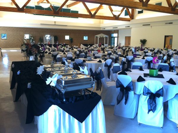 Banquet hall with round tables and white chair covers set up for a formal event