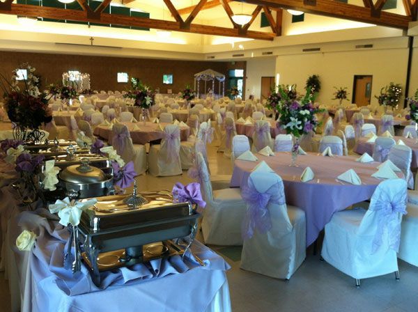 Banquet hall with round, white-clothed tables and buffet chafing dishes set for an event