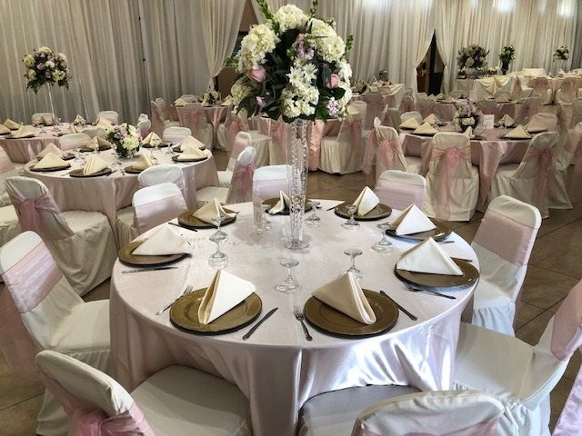 Elegant banquet hall with round tables, pink chair covers, and floral centerpieces arranged for an event