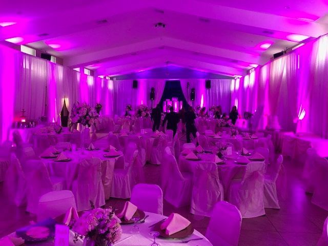 Purple-lit banquet hall with round tables and guests seated under draped ceilings