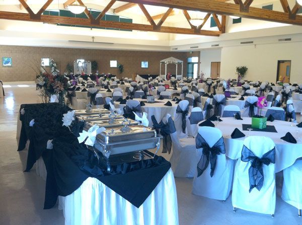 Banquet hall with round tables, white chair covers, and a dessert buffet set up for a formal event