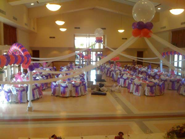 Decorated banquet hall with purple-and-white table settings and balloons for a celebration