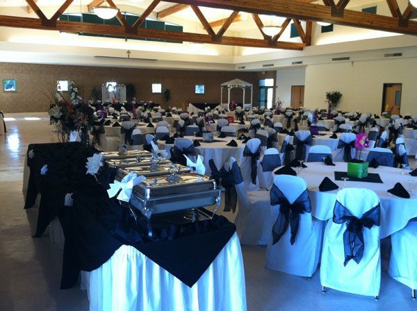 Formal banquet hall with round tables, white chair covers, and guests seated at a reception