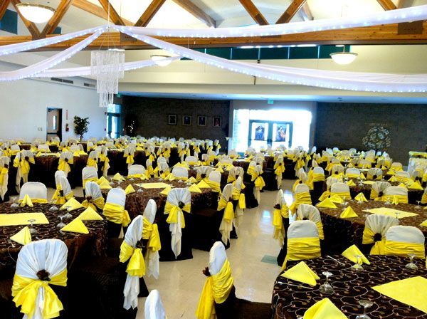 Banquet hall with rows of round tables dressed in white and yellow, ready for a large event