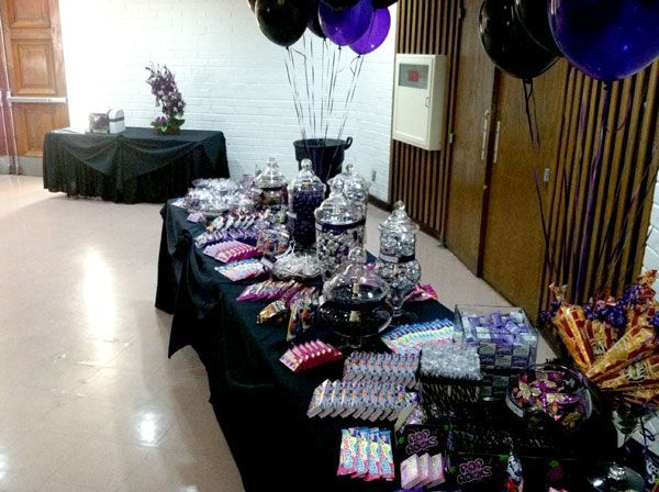 Party dessert table with black tablecloths, balloons, and wrapped treats in a decorated room