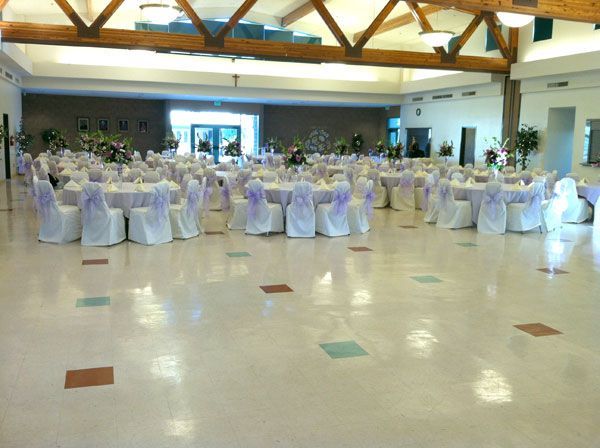 Decorated banquet hall with round tables and white-covered chairs set for an event
