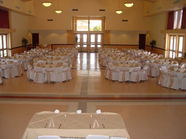 Banquet hall with round tables set for an event and a head table in the foreground
