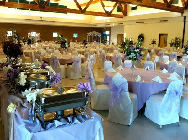Banquet hall with round tables, white chair covers, and a buffet setup for an event