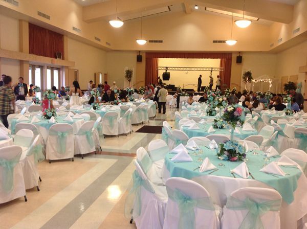 Decorated banquet hall with round tables, white chair covers, and guests seated at a formal event