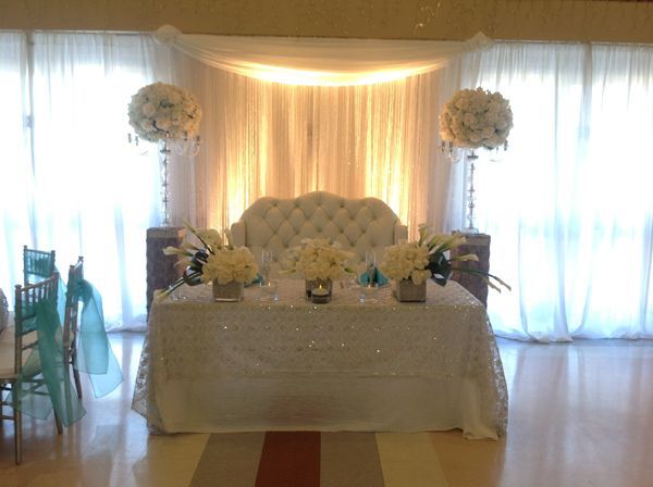 Elegant wedding reception table with white floral centerpieces and cream drapery backdrop