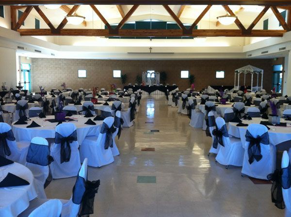 Large banquet hall with round tables and white chair covers, set up for an event or reception