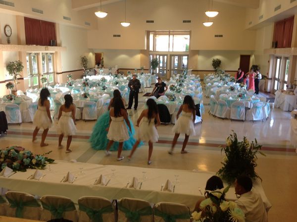 Dancers performing in a bright banquet hall with round tables set for an event