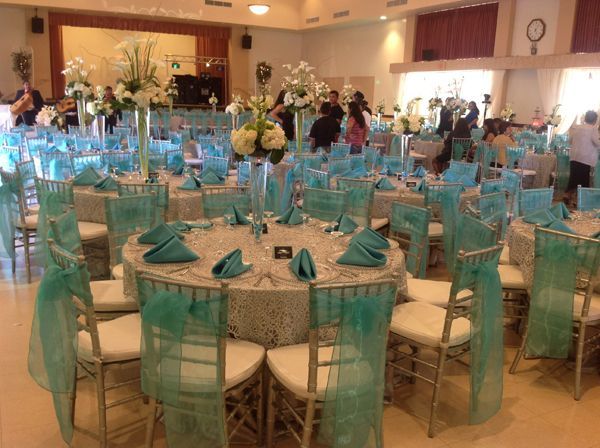Banquet hall with turquoise chair covers and round tables set for an event