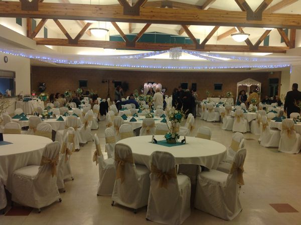 Banquet hall with round, cloth-covered tables and chairs, set for an event under wooden beams