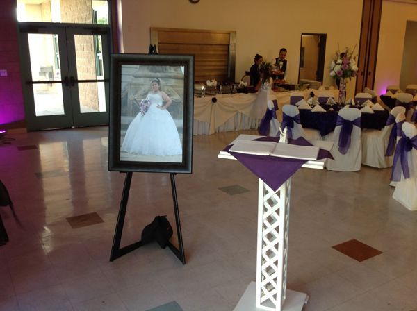Wedding reception hall with a bridal portrait on an easel and purple table decorations