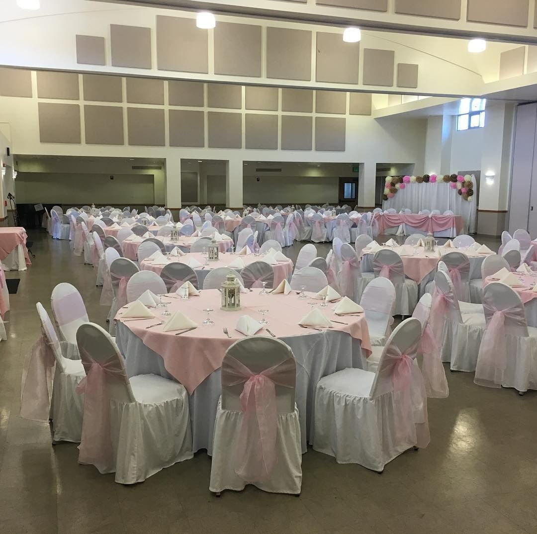 Elegant banquet table set with white linens, wine glasses, plates, and silverware under warm lighting