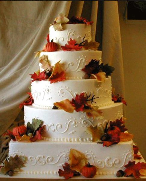 Five-tier white wedding cake decorated with autumn leaves and berries