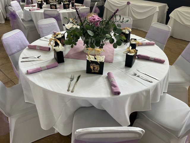Round banquet table with white tablecloth, pink napkins, floral centerpiece, and chairs at a reception venue