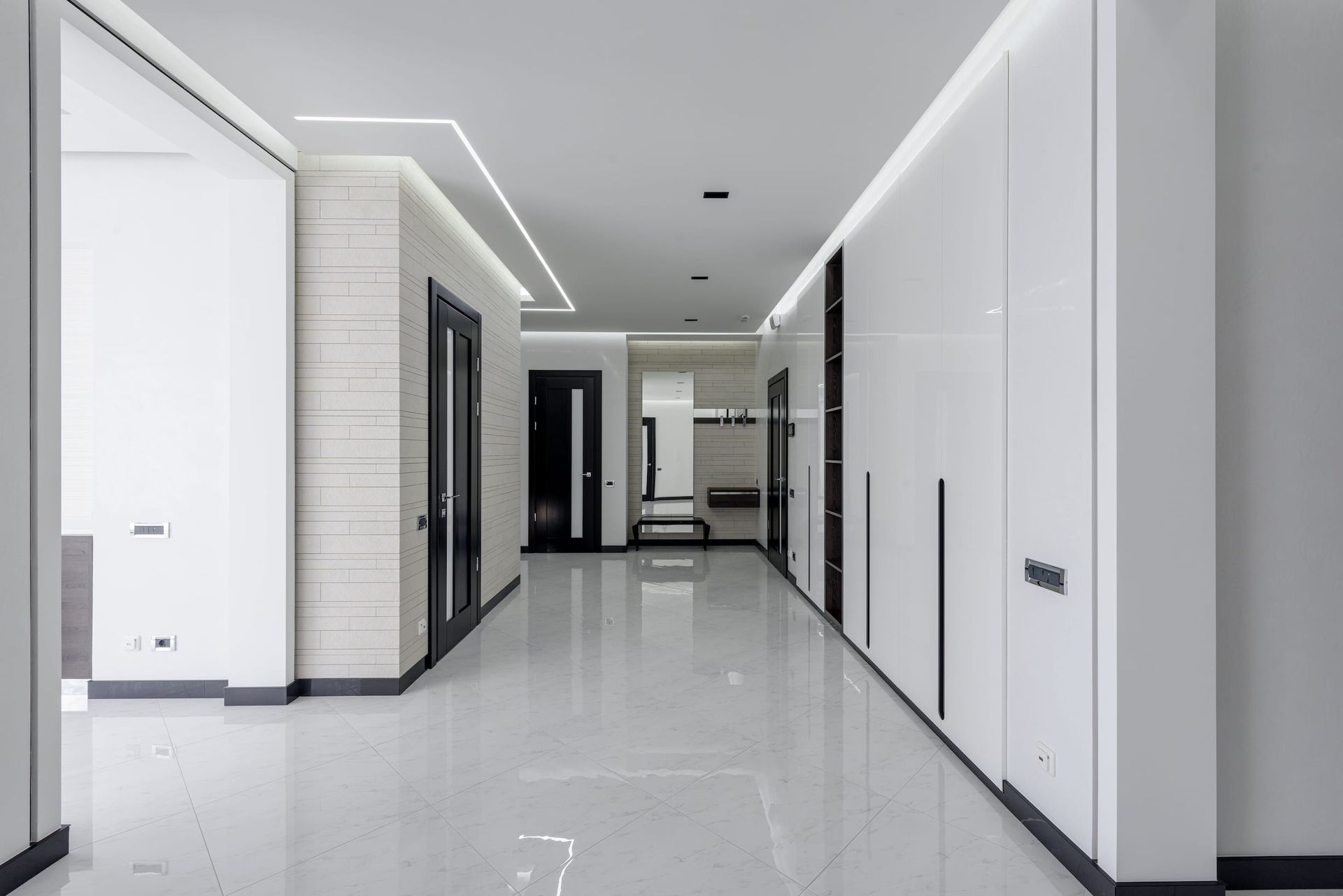 a long hallway with white walls and black doors and high ceilings 