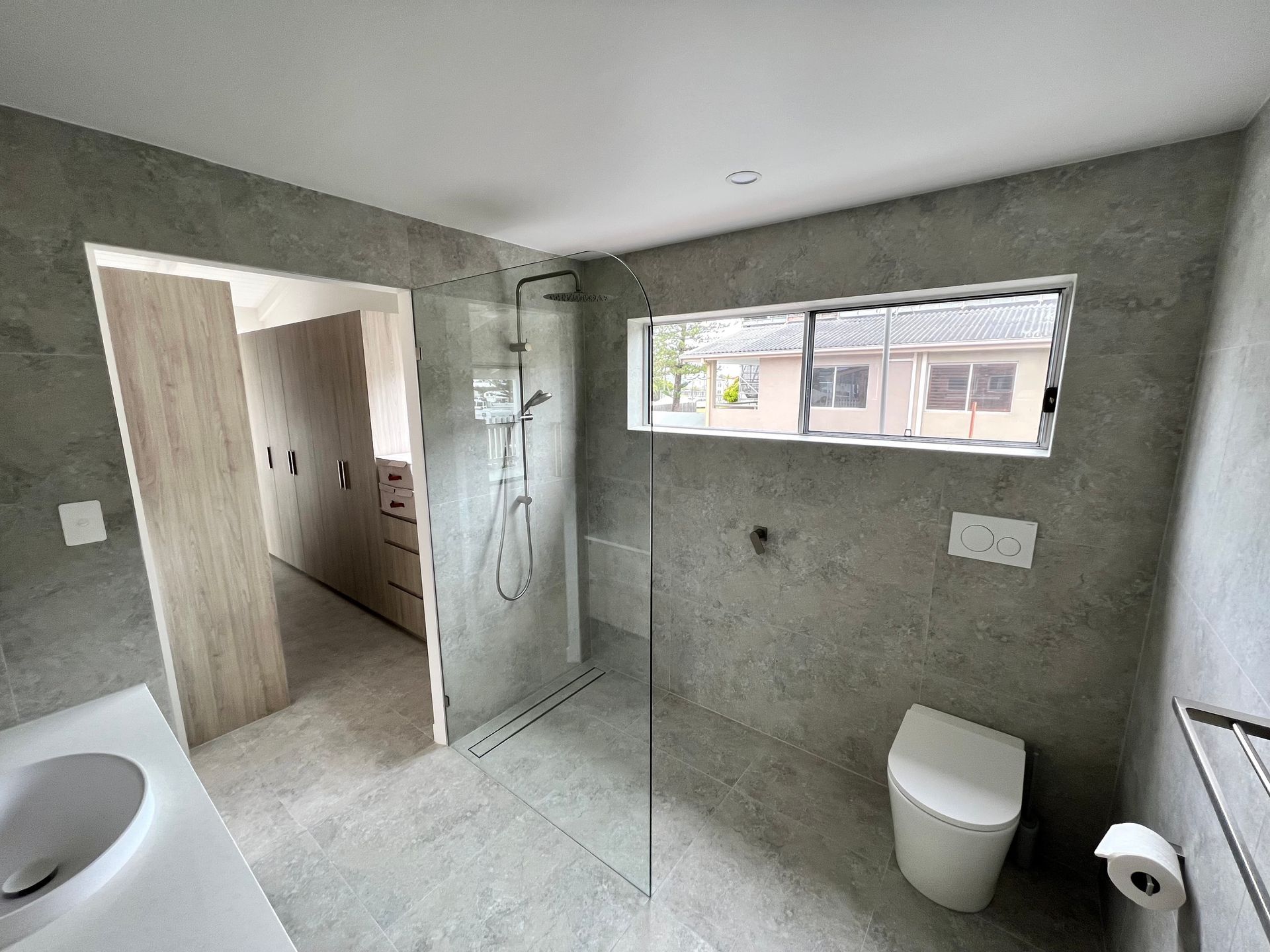 a recently renovated bathroom with a toilet, sink, shower and window.