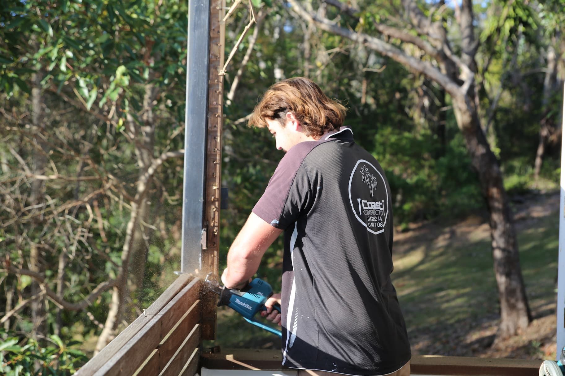 A man extending a home cutting through a piece of timber