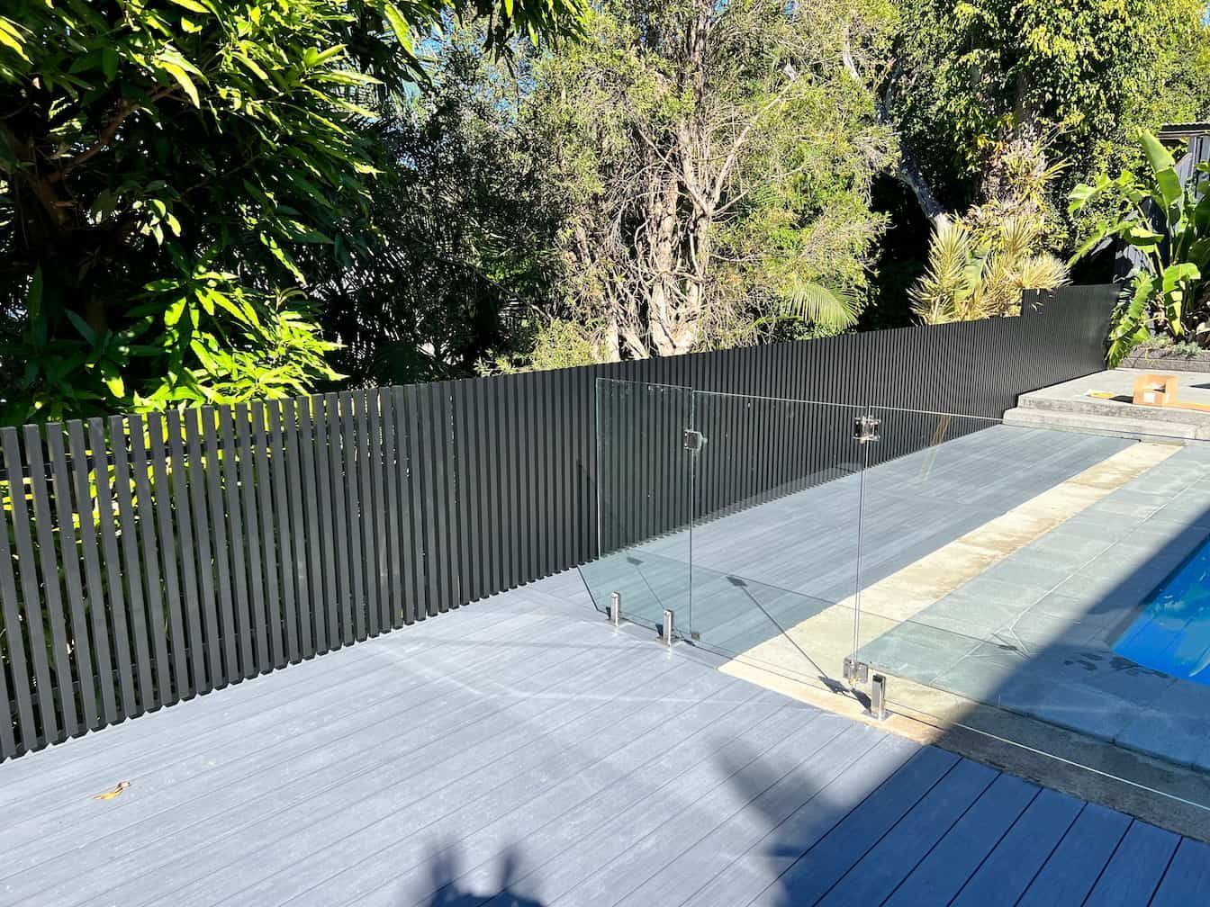 a black fence surrounds a swimming pool with trees in the background