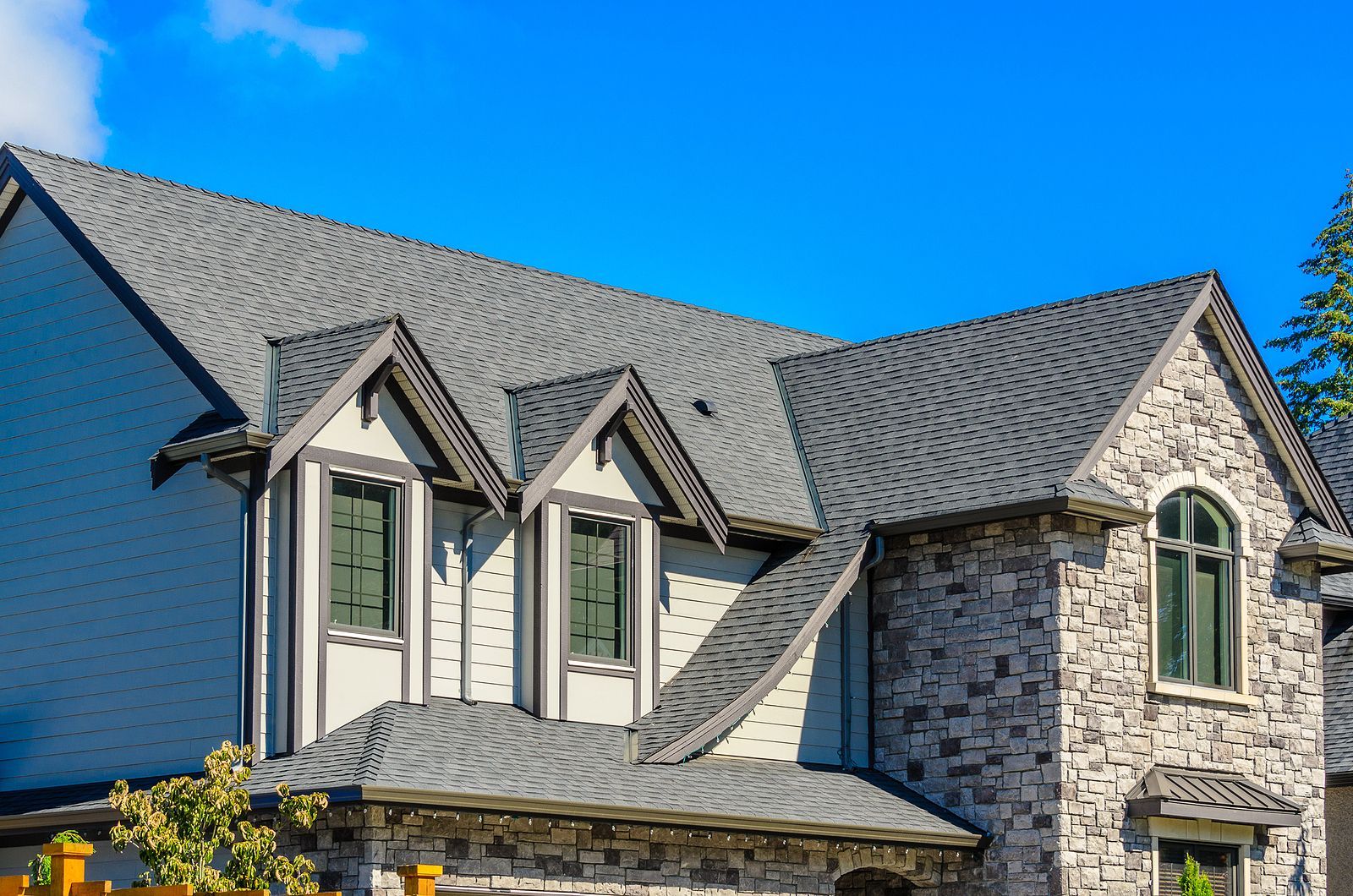 A large house with a gray roof and a blue sky in the background.