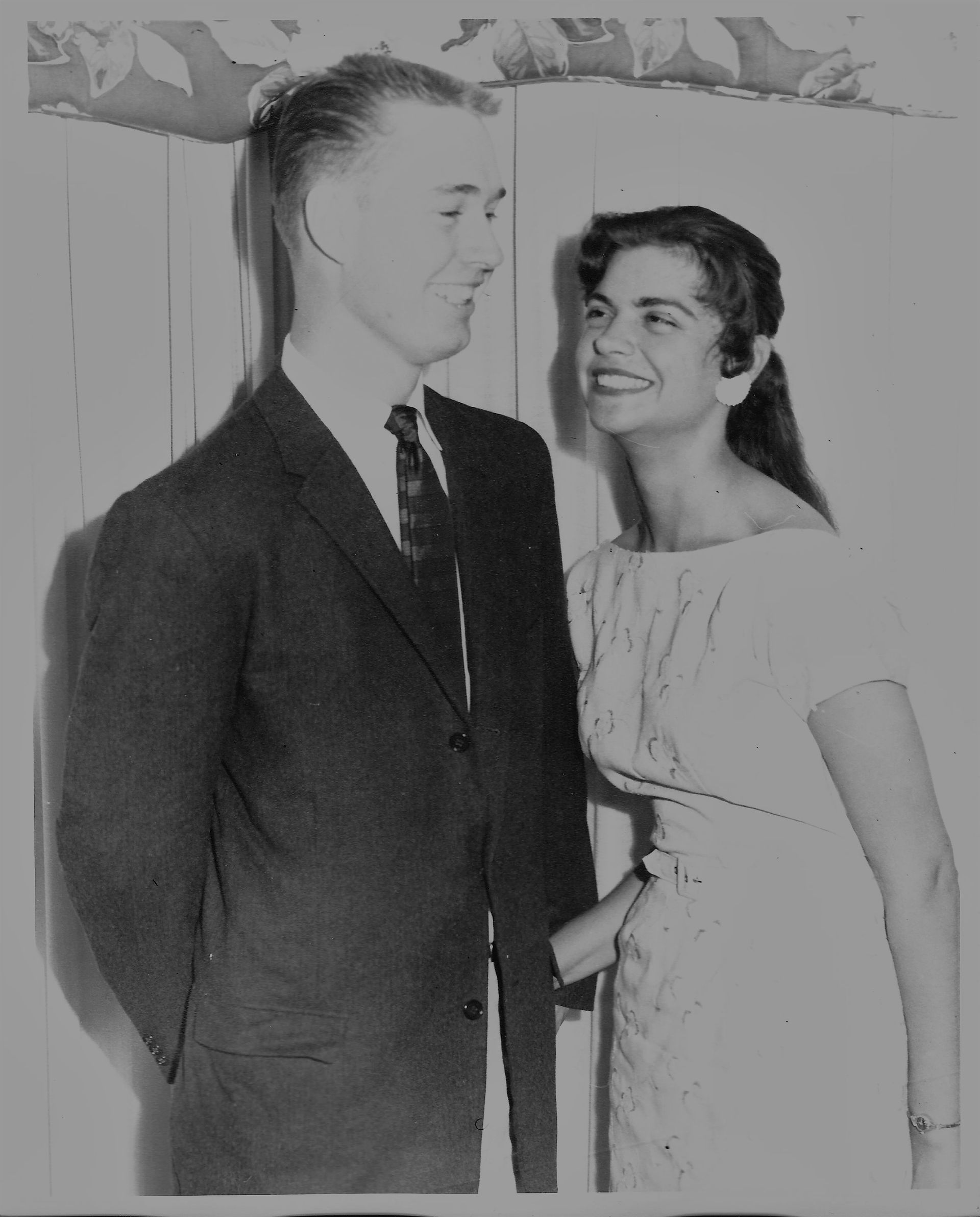 Couple cutting a tiered cake, with a second woman reflected in the mirror.