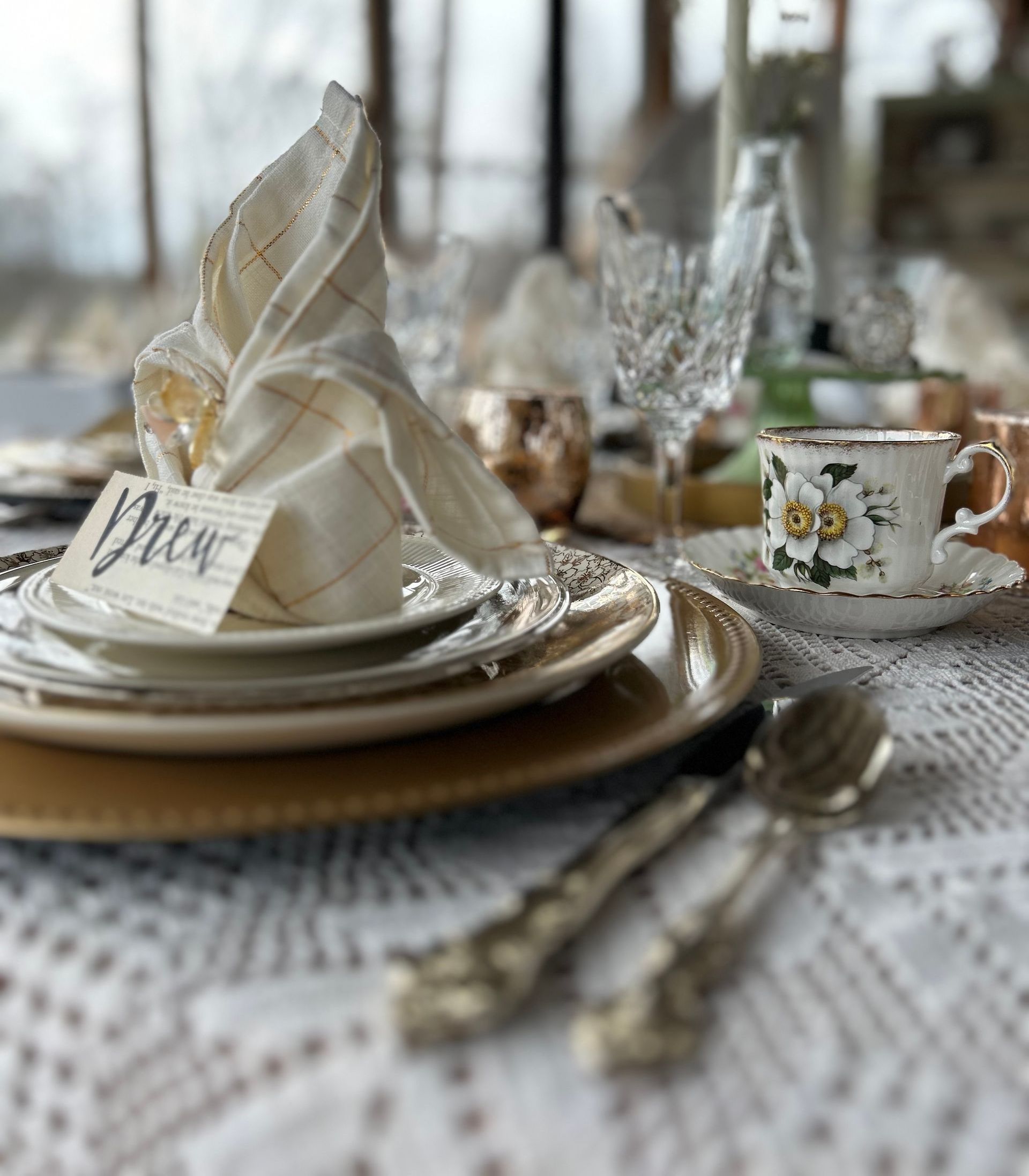 Elegant table setting with gold and silver plates, a folded napkin, and a teacup.