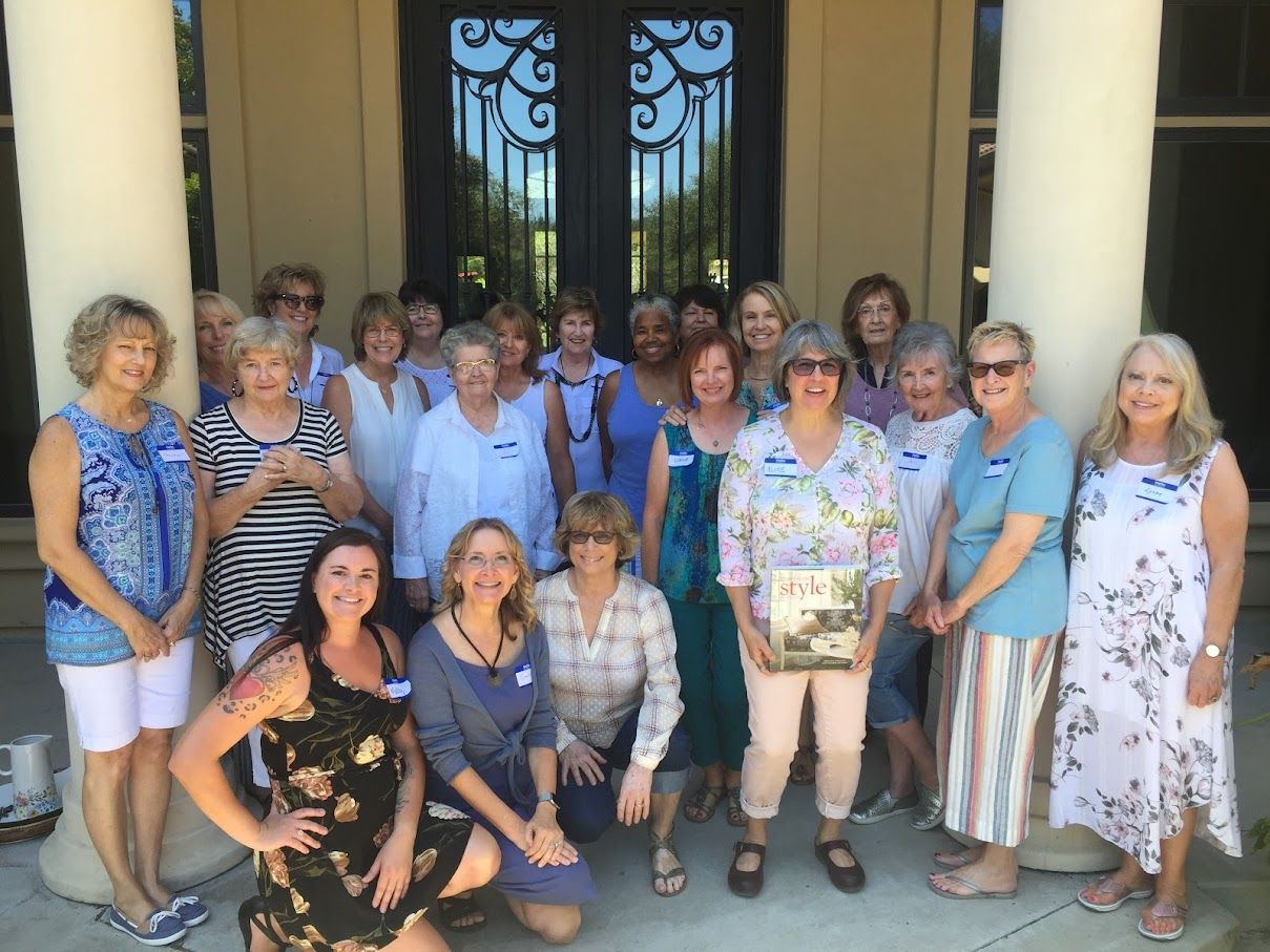Group of women posing outside, smiling, in front of a building with large columns and doors.