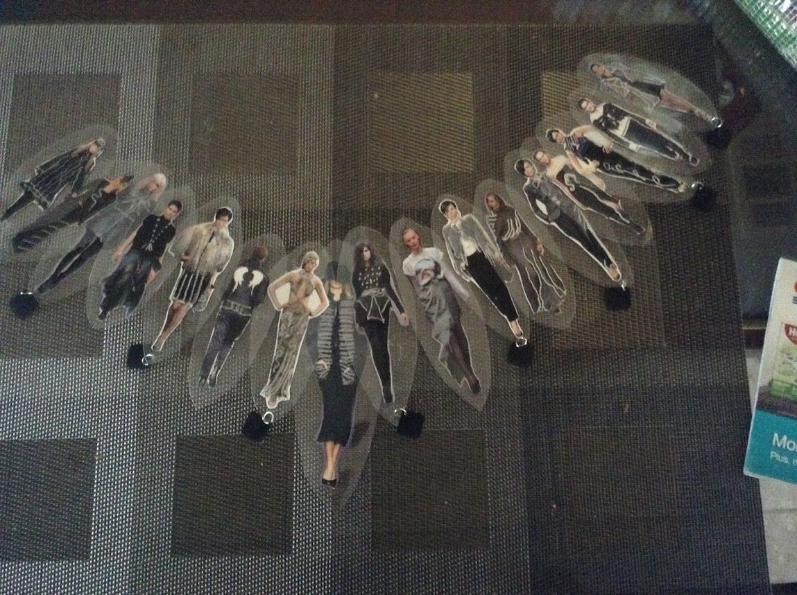 A collection of transparent figures in different outfits, arranged in a decorative curve on a textured surface.
