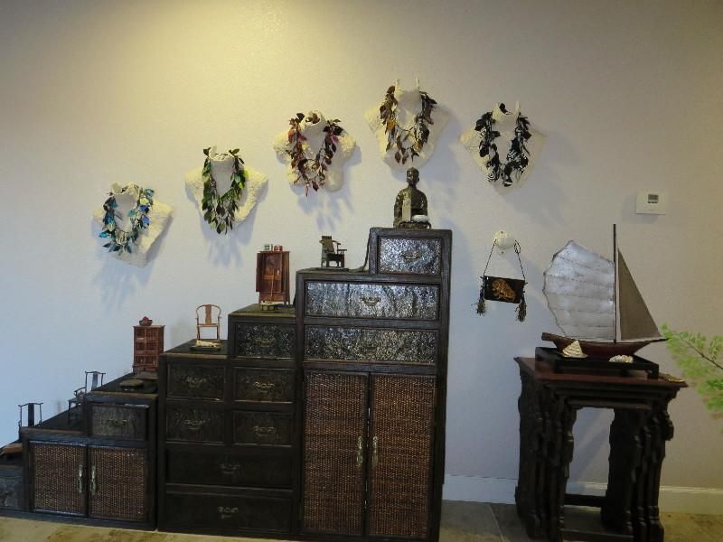 Wall display with lei necklaces and antique furniture.
