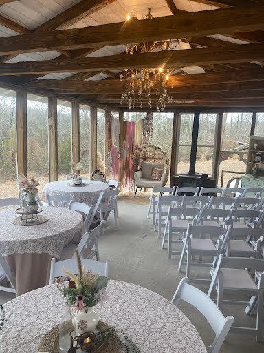 Wedding reception venue with white chairs, round tables, and floral decorations.